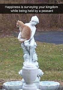 A tall white statue of a woman with a tan cat on her lap. Caption: Happiness is surveying your kingdom while being held by a peasant.