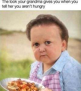 Photo: child with a hairdo and clothing like an old woman would wear, holding a plate of food, looking at the camera with a look of disbelief. Caption: The look your grandma gives you when you tell her you're not hungry.