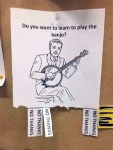sign hanging on a bulletin board, with tear off pieces at the bottom. Sign shows a drawing of a man playing a banjo, and asks, Do you want to learn to play the banjo? Tear-off tabs at the bottom, most of which have been taken, all say NO THANKS