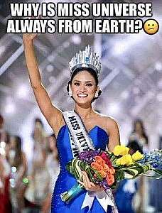 A photo of Miss Universe wearing a huge tiara and a blue strapless dress, waving at the audience and holding a bouquet of colorful flowers, apparently just after she won the title. Caption: Why is Miss Universe always from earth?