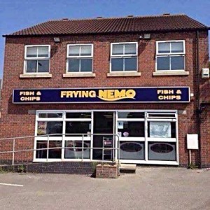 A 2-story brick building with a storefront on the first level, and a sign over with the name of the place, "Frying NEMO fish and chips"