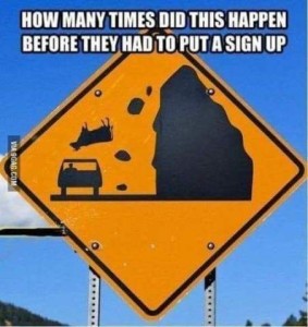 A yellow roadside caution sign with a picture of a huge rock with pieces falling off, and an upside down cow, right over a car that is driving past. Caption: How many times did this happen before they had to put a sign up