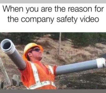 A construction worker with pipes over both arms, standing with arms out like a robot. Caption: When you are the reason for the company safety video.
