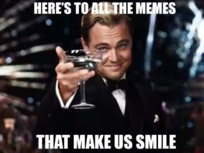 Actor Leonardo DiCaprio dressed in a tuxedo, holding a drink out toward the camera as if making a toast. Caption: Here's to all the memes that make us smile.