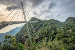A sky bridge, set in a mountainous area, and so tall that you can barely see the ground below.