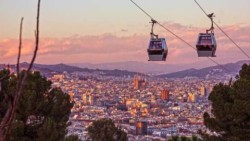 2 sky cars (cable cars) so high above a city that the building are almost indistinguishable