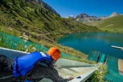 A a person at the top of a water slide going down the side of a massive hill into a lake far below