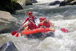 4 people in an inflatable raft, with oars, on the rapids