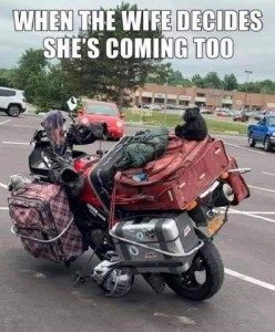 A photo of a motorcycle loaded with multiple suitcases and bags tied onto it, and a little teddy bear on top. Caption: When the wife decides she's coming too