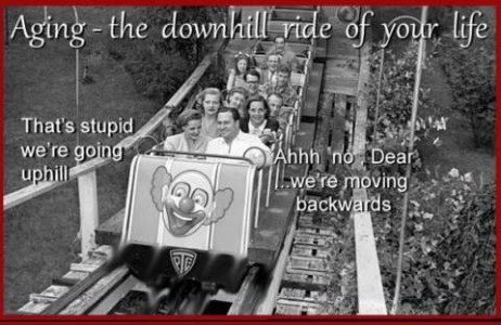 Title: Aging - the downhill ride of your life. Black and white 50's photo of a wooden roller coaster taken from the front of the line of cars, mostly loaded with people with an older couple in the front. Text to the left of the woman: "That's stupid, we're going uphill." Text to the right of the man: "Ahhh no, Dear...we're moving backwards."