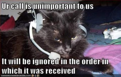 Black or gray cat laying down with a receptionist-type headset on. Caption: Ur call is unimportant to us. It will be ignored in the order in which it was received.