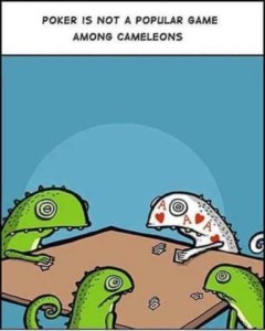 3 lizards sitting around a table playing cards. 3 are green. One is white with hearts and the letter A on his skin. Caption: Poker is not a popular game among chameleons.