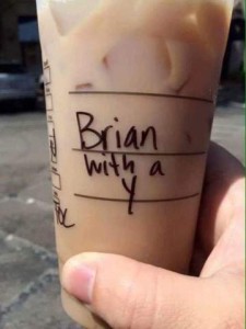 A hand holding an iced coffee in a plastic to-go cup upon which is hand written, "Brian with a Y"