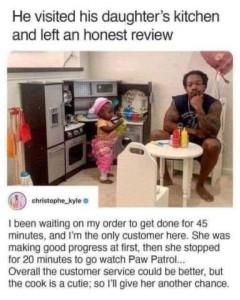 Text: He visited his daughter's kitchen and left an honest review. Followed by a photo of a muscular daddy sitting on a tiny chair at a tiny table surrounded by tiny kitchen appliances and a tiny little girl dressed in pink wearing a tiny hat. Text at the bottom: I been waiting on my order to get done for 45 minutes, and I'm the only customer here. She was making good progress at first then she stopped for 20 minutes to go watch Paw Patrol... Overall the customer service could be better, but the cook is a cutie; so I'll give her another chance.