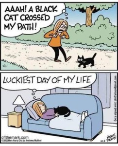 Comic: top frame shows a woman walking down the street with a black cat walking across the path in front of her; thought bubble says, "Aaah! A black cat crossed my path!" 2nd frame shows her napping on a davenport with a black cat laying on top of her; thought bubble says, "Luckiest day of my life"