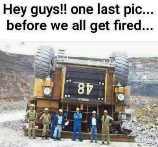Photo of a massive piece of construction equipment upside down, wheels in the air, as 6 workers in hard hats pose in front of it. Caption: Hey guys!! One last pic...before we all get fired...