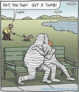 Cartoon of 2 mummies kissing on a park bench. Old man walking his dog behind them says, "Hey you two! Get a tomb!"