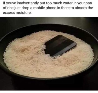 Caption: If you've inadvertantly put too much water in your pan of rice just drop a mobile phone in there to absorb the excess moisture. Photo of a pan of raw white rice with a smartphone laying in it.