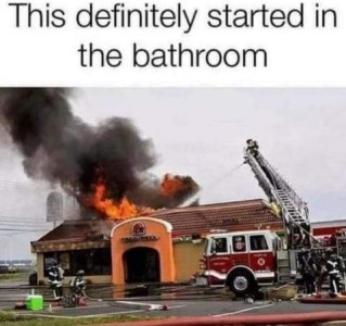 Photo of a Taco Bell with fire and smoke coming out of the roof as a fire truck is spraying water on it. Text: This definitely started in the bathroom.