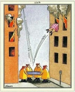 Cartoon. 2 tall buildings are on fire. 4 firemen are between them, holding a rescue net. There are lines indicating someone had jumped down into it, then bounced back up into the other burning building. The firemen are looking up at the back half of a woman on her way in the 3rd floor window.