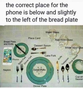 Photo of an elaborate table setting with descriptions of where each piece - Bread plate and knife, place card, dessert spoon, salad fork, dinner fork, cake fork, napkin, salad plate, dinner plate, water glass, red wine glass, white wine glass, knife, teaspoon, soup spoon, cup and saucer - are to be placed. Caption: the correct place for the phone is below and slightly to the left of bread plate.