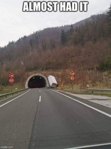 Photo of a road with a tunnel going into the side of a mountain; directly to the right of the tunnel entrance is a semi-truck crashed into the mountainside. Caption: Almost had it!