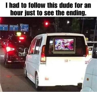 In a line of traffic is an SUV with a TV facing out the back window. Caption: I had to follow this dude for an hour just to see the ending.