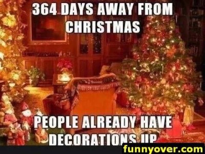 Photo of a brightly decorated room with a cozy chair, a Christmas tree, little dolls and Santas on the hearth, the fireplace fully covered with tinsel, gifts under the tree, and a poinsettia on the coffee table. Caption: 364 days away from Christmas. People already have decorations up.