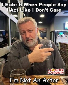 Photo of a man sitting in a restaurant holding a beer glass in one hand; another sits on the table in front of him. He is looking at the camera with a serious look on his face. Caption: I hate it when people way I act like I don't care. I'm not an actor."