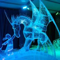 a unicorn with a little girl reaching up to touch his nose.