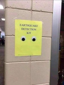 Yellow sign taped to a concrete block wall has two googly eyes stick to it, with the words, "Earthquake detection kit."