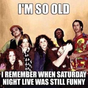 70s photo of Jim Belushi, Lorraine Neuman, Jane Curtin, Gilda Radner, Arsinio Hall, Dan Ackroyd, and Chevy Chase. Caption: I'm so old I remember when Saturday Night Live was still funny.