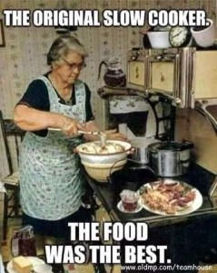 Photo of an elderly woman wearing a dress under a full flowered apron, working in a kitchen with wallpaper; she is mixing something in a big bowl, with a plate of food on her counter (either a Hoosier, or a very old stove maybe?). Caption: The original slow cooker. The food was the best.