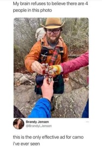 A photo of a man in hiking gear facing the camera, and two other hands reaching in to clink FOUR small bottles together before drinking. Caption: My grain refuses to believe there are 4 people in this photo. Comment below: This is the only effective ad for camo I've ever seen.