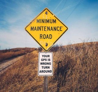 Road sign: Minimum Maintenance Road. Sign beneath it, on the same post: Your GPS is wrong, turn around.