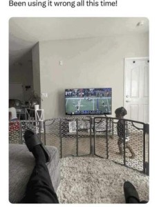 Caption: Been using it wrong all this time!" Photo of someone relaxed with his feet up, watching TV while taking the photo. He is surrounded by baby gates, and his toddler is on the outside of his tidy space within.