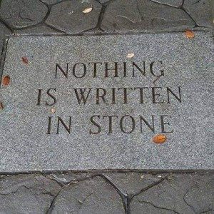 A large stone brick inset into concrete, inscribed with the words, "Nothing is written in stone."