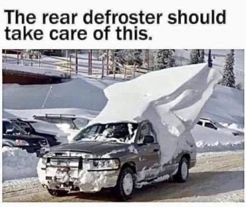 Photo of a car driving down a road that's clear but surrounded by deep snow; the car has about 10 feet of snow piled on top and standing high off the back of it. Caption: The rear defroster should take care of this.
