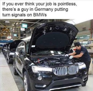 Photo of a car on an assembly line; the hood is up and someone is working on the engine. Caption: If you ever think your job is pointless, there's a guy in Germany putting turn signals on BMWs