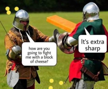 Two men dressed as knights with helmets, heavy leather jackets, and metal guards over their hands and arms; one is holding a sword, one is holding a big orange block of cheese. The first guy asks, "how are you going to fight me with a block of cheese?" The other guy replies, "It's extra sharp."