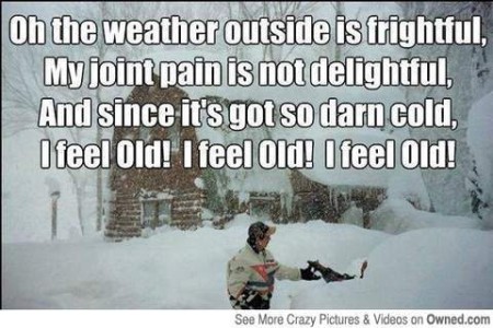 Photo of someone standing in deep snow, in front of a snow-covered log cabin; the snow looks to be at least a few feet deep. Caption: Oh the weather outside is frightful, My joint pain is not delightful, And since it's got so darn cold, I feel old! I feel old! I feel old!