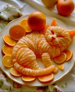 Brilliant artistic rendition of a cat laying on its side, head turned to look up. It is made entirely out of orange sections.