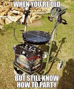 Photo of a rolling walker; where the seat would be is a BBQ grill; there is a beverage holder near the right handle with a beer in it; there is a horn with a bulb on it near the left handle. There's a case of beer on the foot rest. Caption: When you're old but still know how to party.