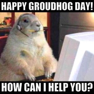 Photo of a groundhog sitting at a computer at a desk wearing headphones with a microphone and a pencil in his mouth. Caption: Happy groundhog day! How can I help you?